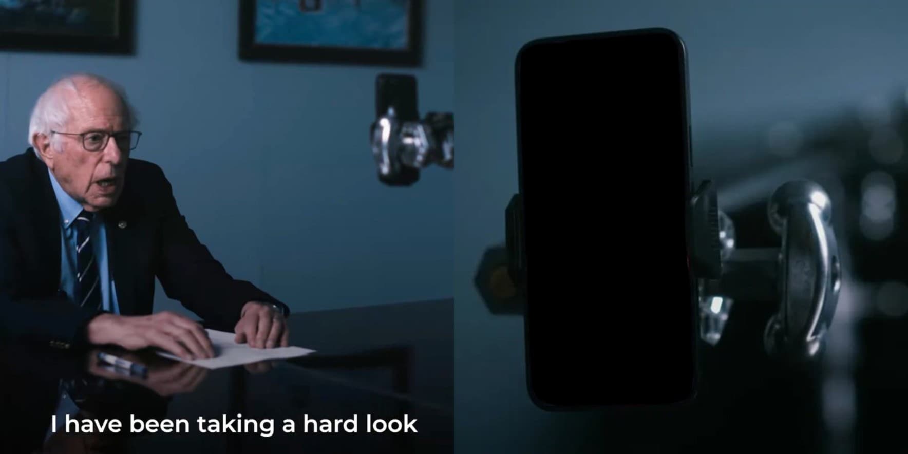 Two-panel dark blue scene showing Bernie Sanders seated at a table on the left and a close-up camera aimed toward a tall blacked-out rectangle on the right. White text along the bottom reads, “I have been taking a hard look.”
