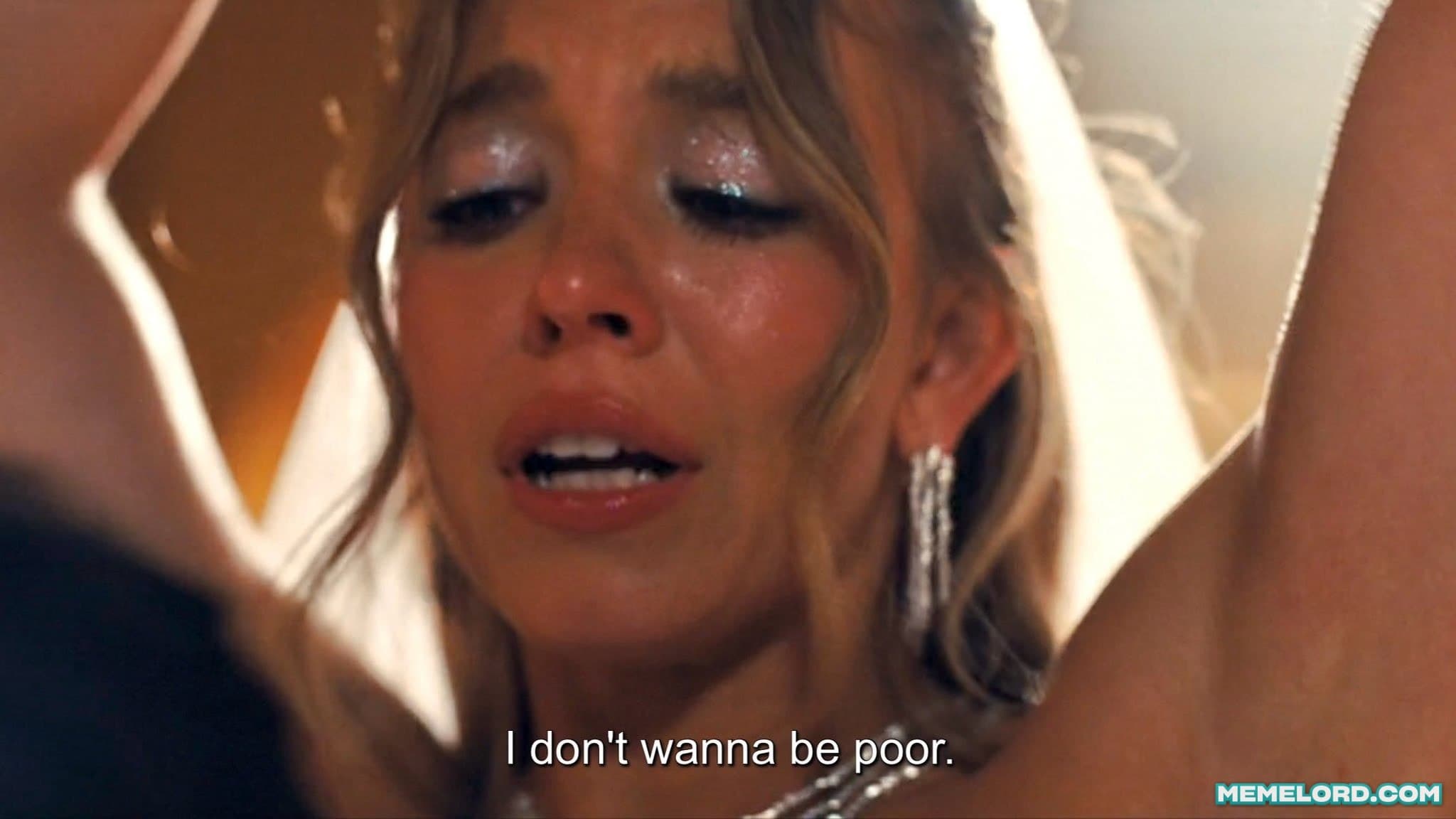 A close-up of a blonde woman with glittery eye makeup and dangling earrings making a distressed expression while seated in a car; the subtitle reads “I don’t wanna be poor.”