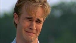 Close-up of James Van Der Beek as Dawson Leery with blonde hair, face scrunched up in an exaggerated ugly-cry with furrowed brow and downturned mouth, outdoors with green foliage behind him.