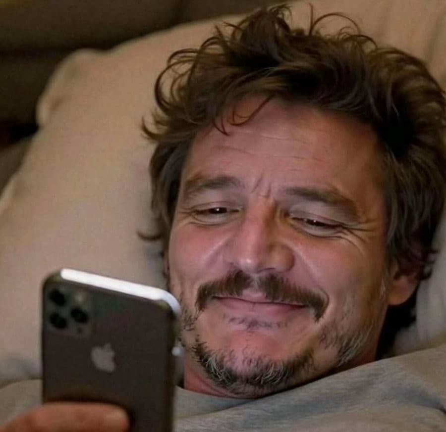 Pedro Pascal smiling at phone in bed meme template