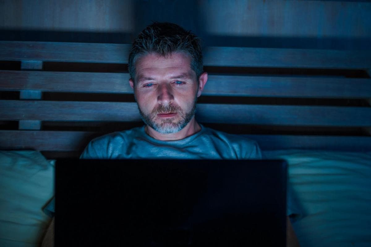 Person glued to a laptop in bed at night