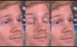 Close-up reaction GIF of Drew Scanlon, a fair-skinned man with short brown hair, turning toward the camera and doing a slow, exaggerated blink followed by rapid eye twitches, conveying stunned disbelief or confusion.