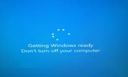 Solid blue Windows 10-style screen with a ring of white loading dots at center, the text 'Getting Windows ready' in white, and a smaller line below reading 'Don't turn off your computer'.