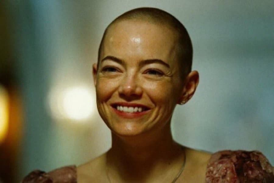 Emma Stone smiling through pain Bugonia