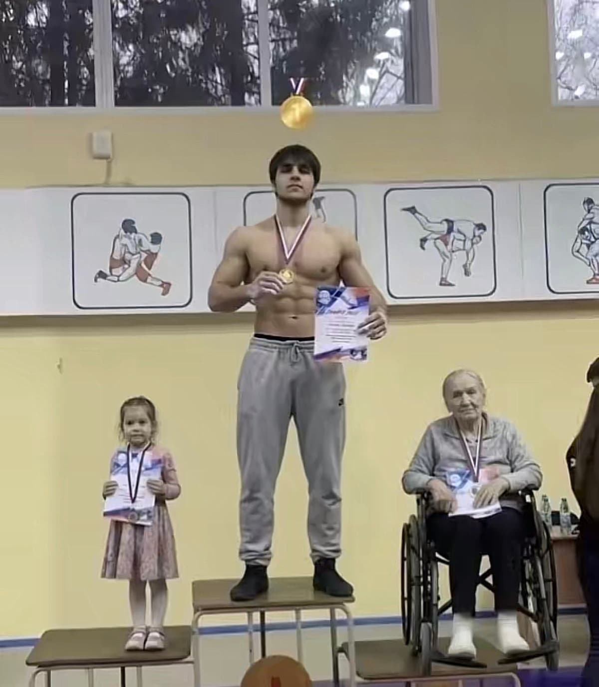 Muscular Guy on a podium with a young girl and an elderly woman