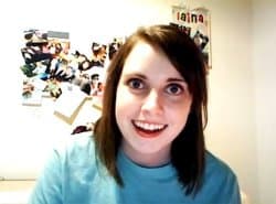 Close-up of a young woman with wide eyes and an intense smile staring directly at the camera