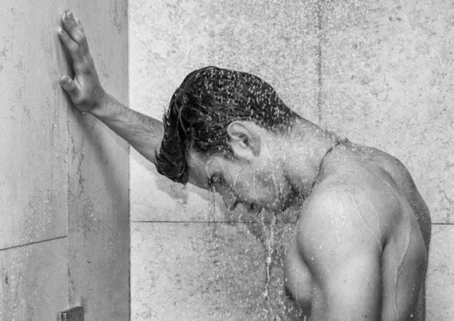 Sad man standing in shower