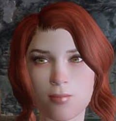 Close-up of a female Skyrim NPC with red hair and a blank, neutral expression, rendered in the game's 3D graphics style against a stone wall background