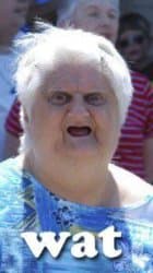 An elderly woman with gray hair making a contorted, confused face with her lips pulled back and dentures removed, looking utterly baffled at something off camera.